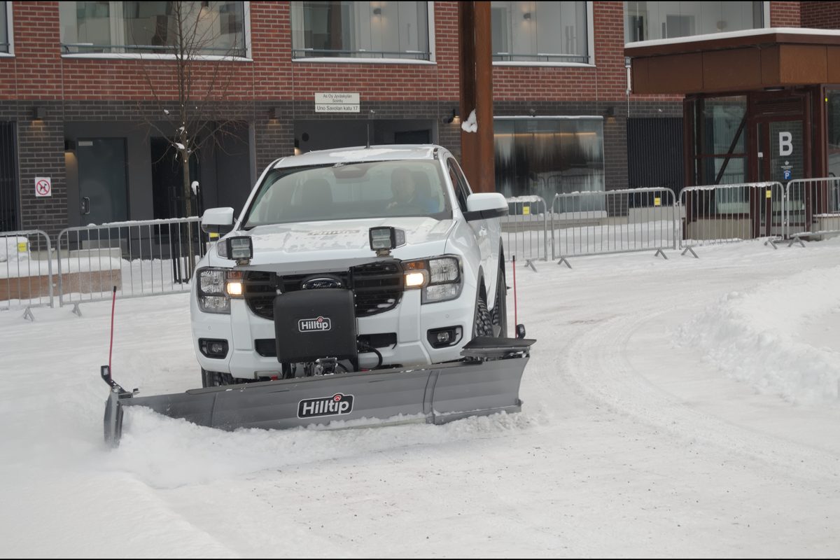 Pickup truck with a snow plow clearing a snowy lot